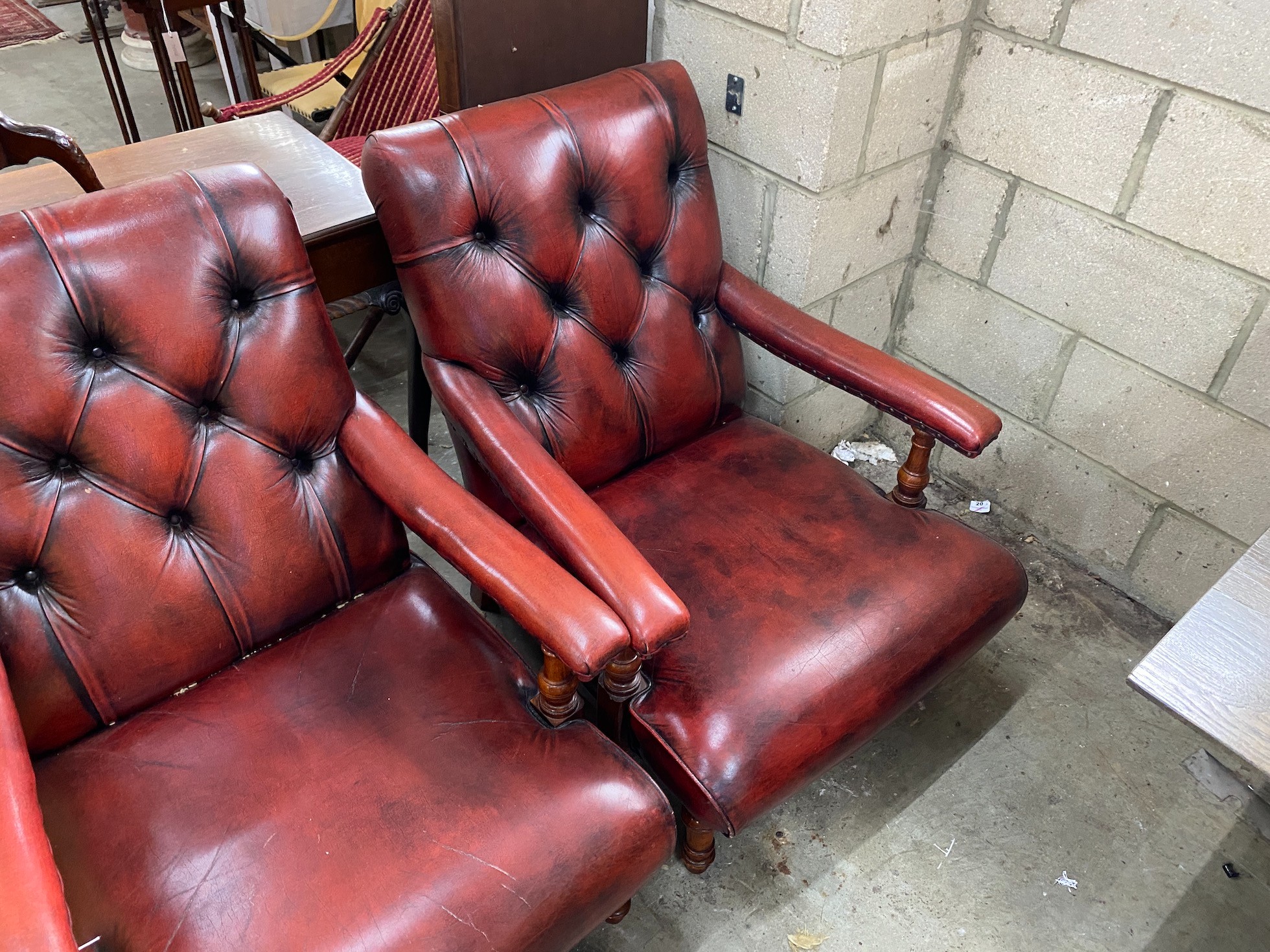 A pair of Victorian style button back burgundy leather Howard style open armchairs, width 69cm, depth 88cm, height 86cm